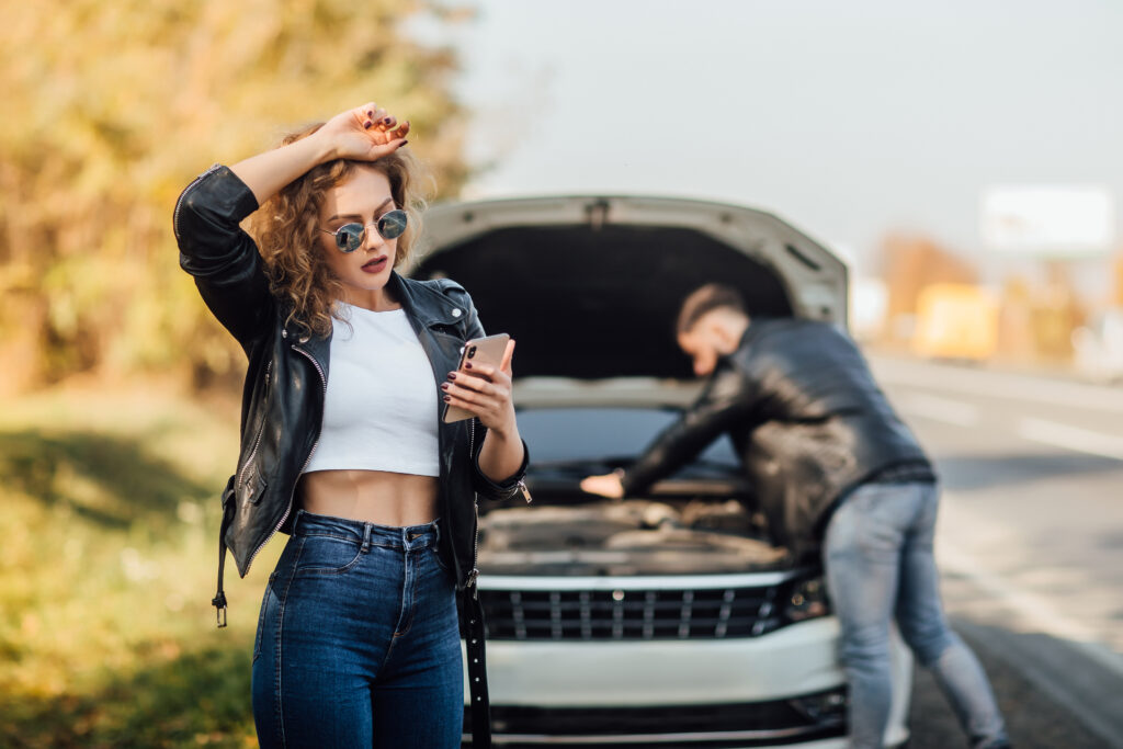 Retrato de uma mulher jovem e bonita usando seu telefone celular enquanto solicita assistência para o carro.